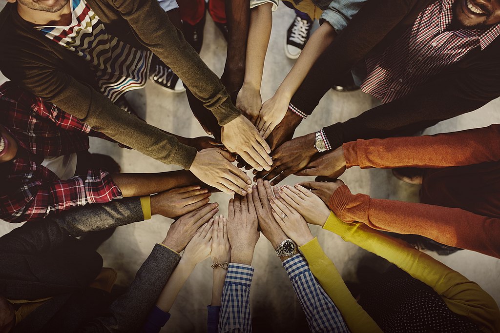 Group of people putting their hands together.