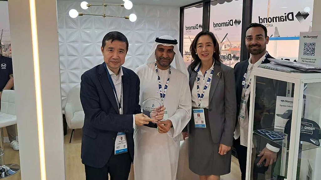 A group of four professionals stands together in a modern office space, smiling and holding an award in celebration.