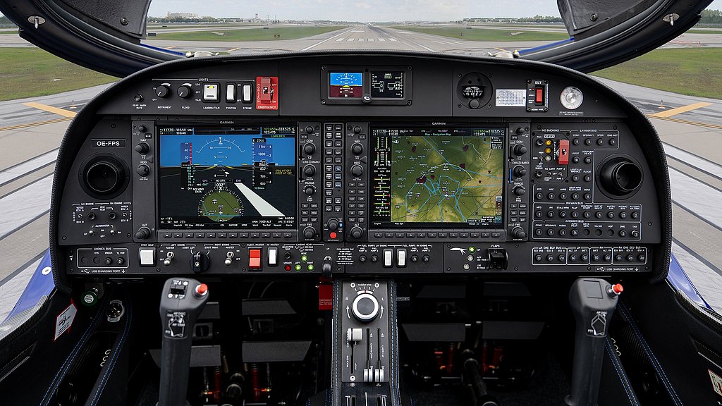 The cockpit of a DA42-VI aircraft features advanced navigation screens and controls, with a clear view of the runway ahead.