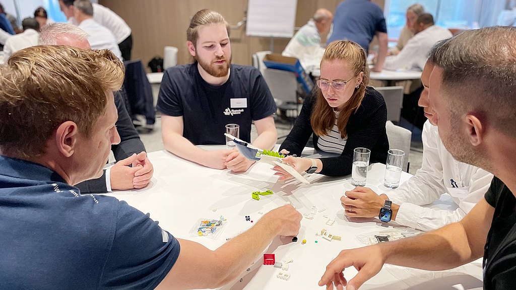 Group of people building a Lego aircraft. 