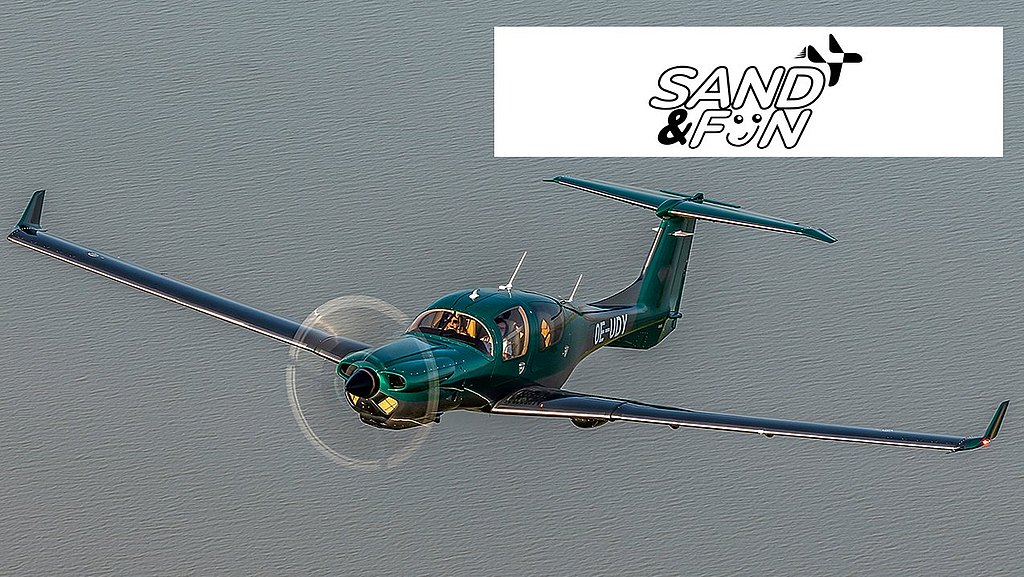 A sleek green aircraft soars gracefully above a calm body of water, showcasing its elegant design and spinning propeller.