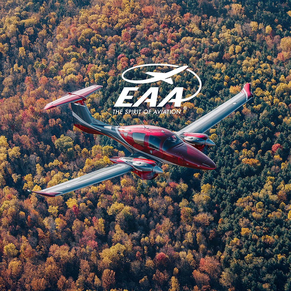 An elegant DA62 aircraft flies over a colorful landscape of trees, highlighting the rich hues of fall in the background.