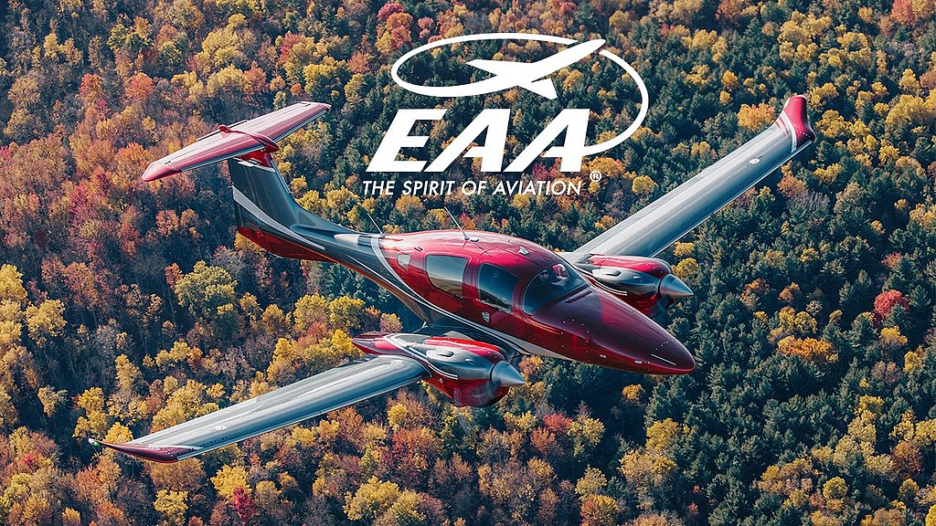 An elegant DA62 aircraft flies over a colorful landscape of trees, highlighting the rich hues of fall in the background.
