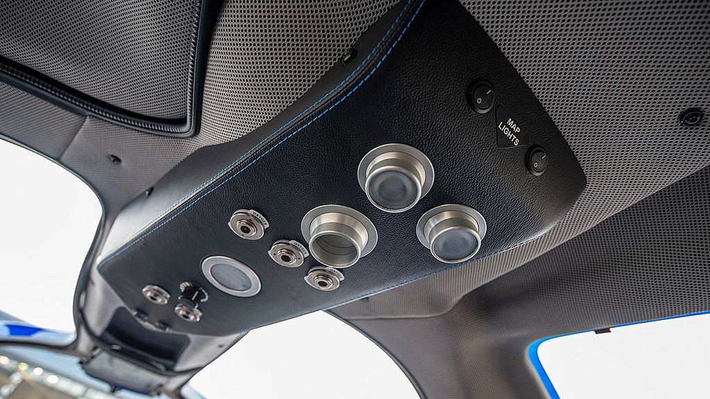 An overhead view of a sleek aircraft interior featuring control buttons and lights, showcasing modern design elements.