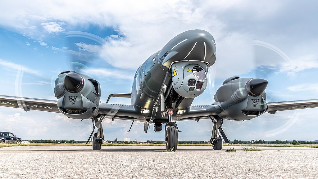 DA62 MPP standing on the tarmac with a camera mounted to the nose of the aircraft.