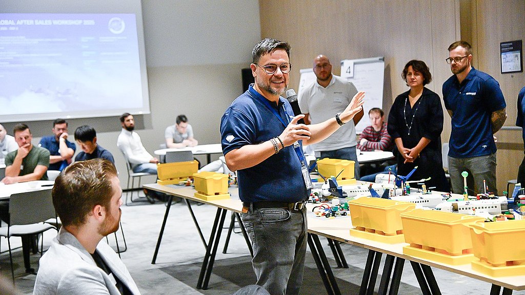 A man speaking with a microphone to the participants of the workshop.
