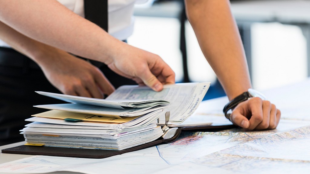 Students looking into a binder lying on a desk with a map. 