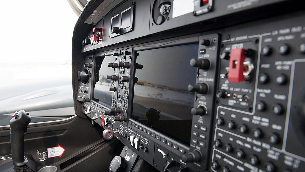 The cockpit features an array of controls, screens, and instruments, showcasing a modern aircraft's advanced technology.
