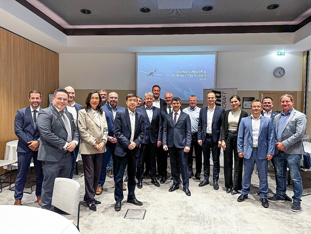 A diverse group of professionals stands together at a conference, smiling and dressed in business attire, showcasing collaboration.