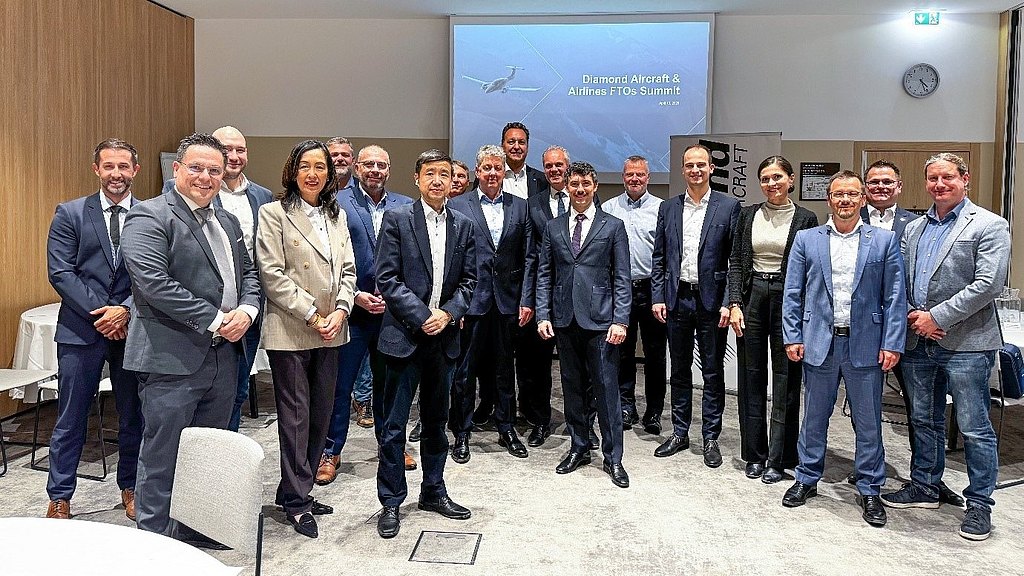 A diverse group of professionals stands together at a conference, smiling and dressed in business attire, showcasing collaboration.