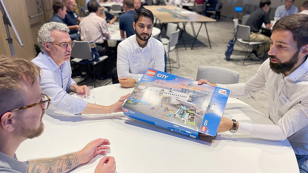 Group of people opening a Lego aircraft box. 