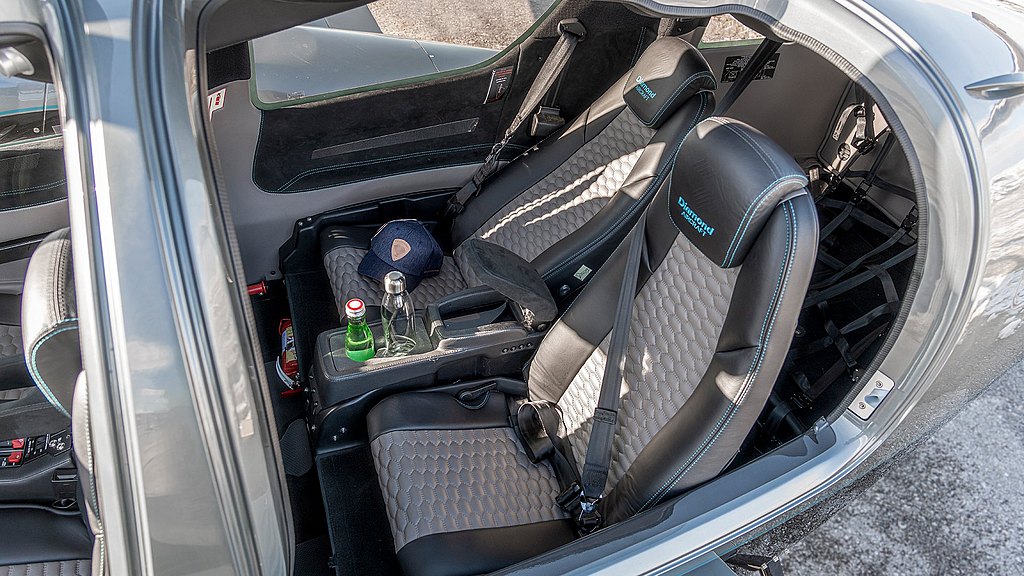 A well-designed aircraft interior features two ergonomic business seats and a center console with drinks.