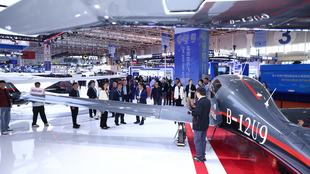 A sleek, modern DA50 RG aircraft is showcased at an exhibition, surrounded by an engaged crowd of attendees and industry professionals.