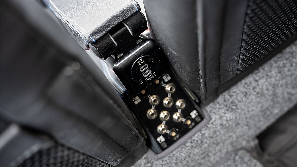 The image highlights a USB charging outlet with a 100W label, integrated into a stylish aircraft middle arm rest for convenient access.