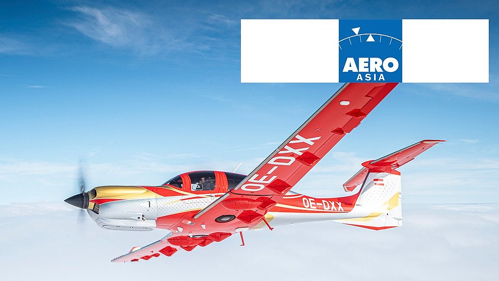 A vibrant red and gold DA50 RG aircraft soars through a clear blue sky, showcasing its sleek design and powerful propeller.