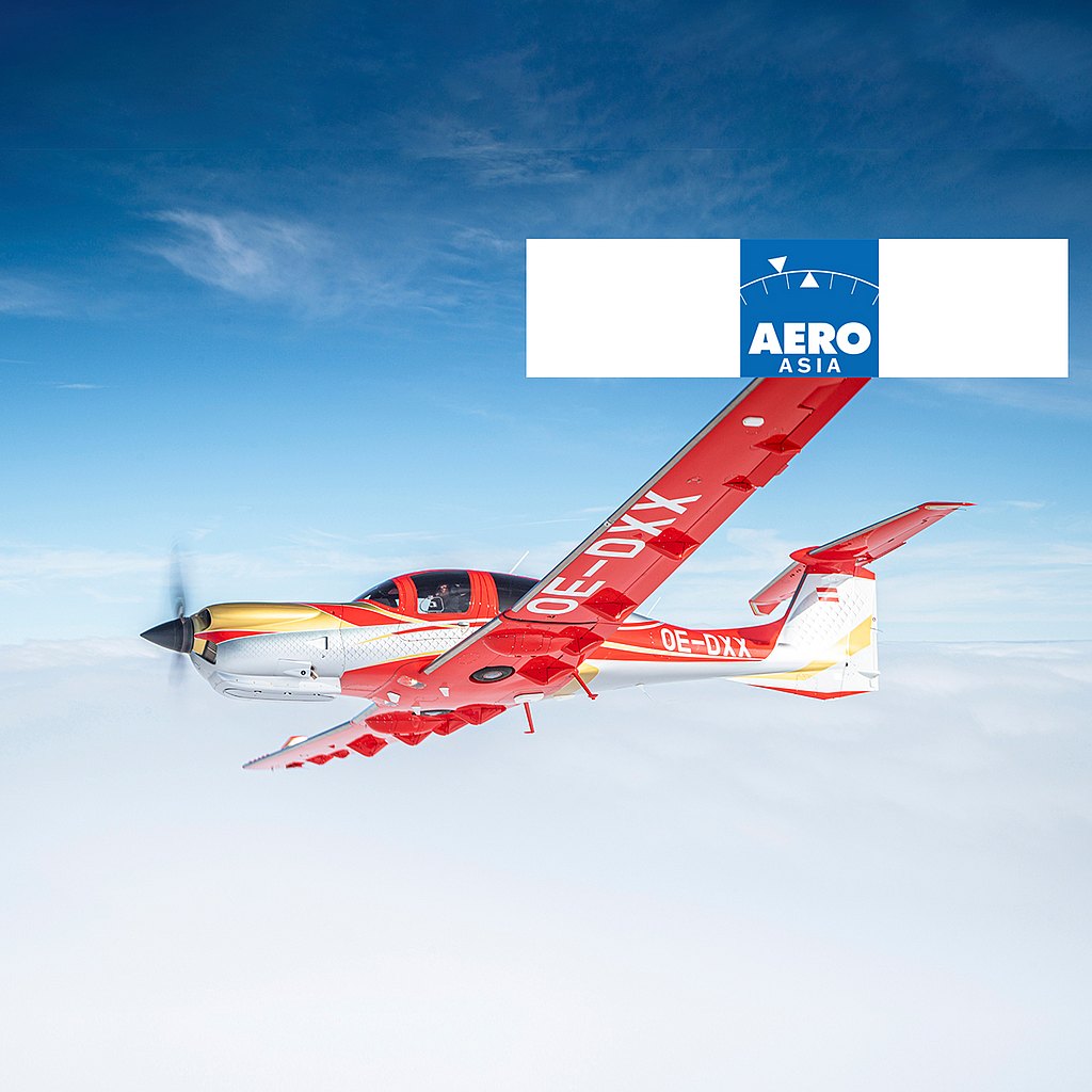 A vibrant red and gold DA50 RG aircraft soars through a clear blue sky, showcasing its sleek design and powerful propeller.