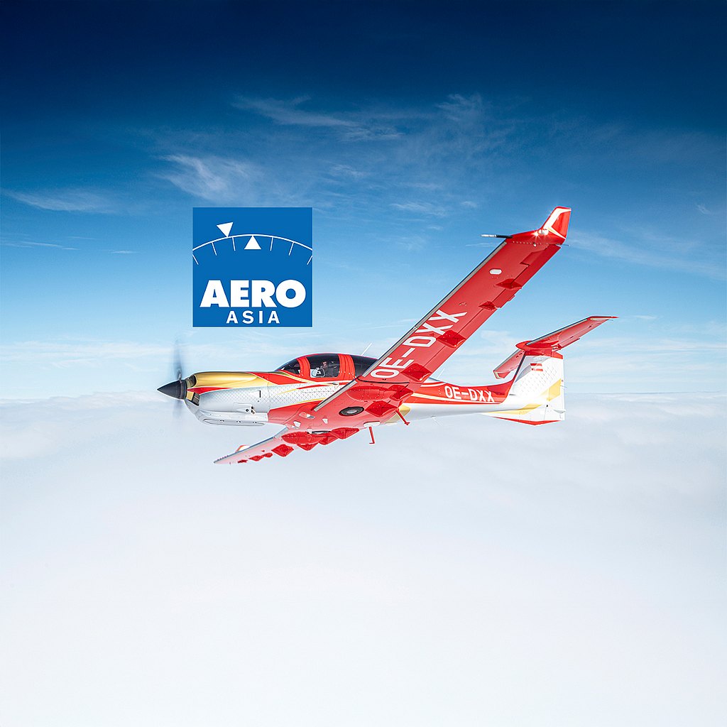 A vibrant red and gold DA50 RG aircraft soars through a clear blue sky, showcasing its sleek design and powerful propeller.