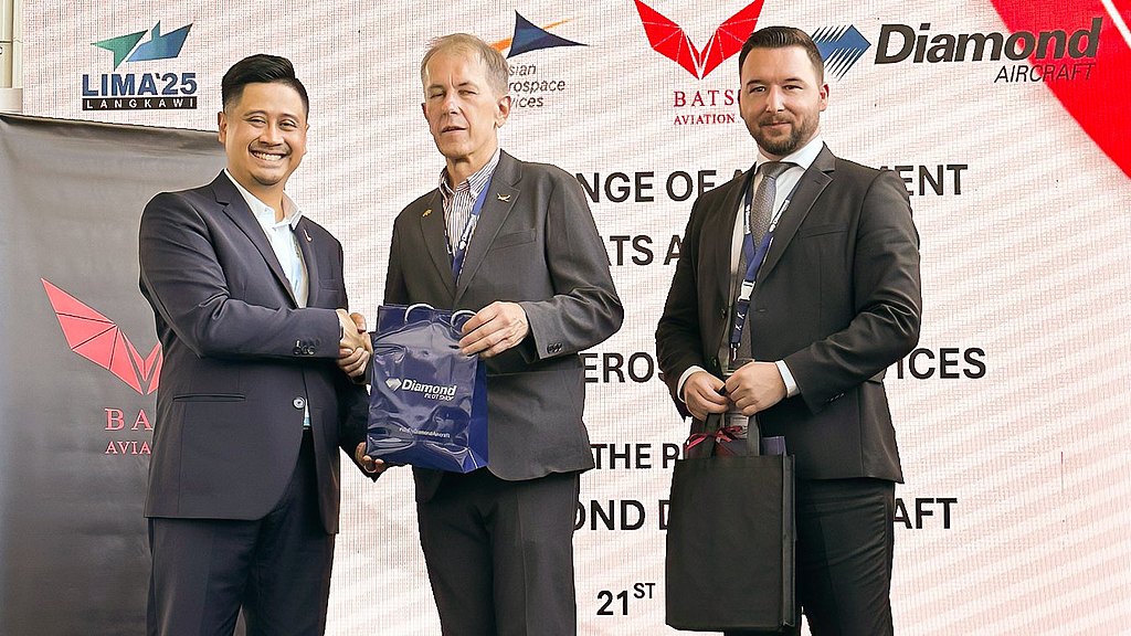 Three men in suits standing at a stage shaking hands. 