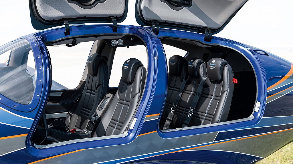 The interior of a sleek blue DA50 RG aircraft features two open doors, revealing modern black seats and interior.