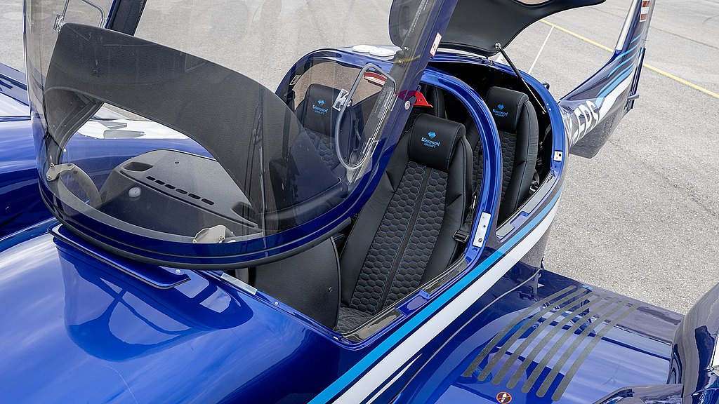 Inside the cockpit of a blue DA42-VI aircraft, showcasing comfortable seating and a stylish design with a clear canopy overhead.