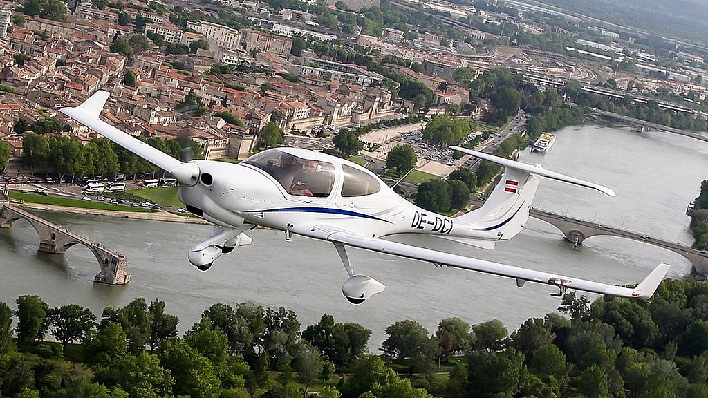 DA40 NG flying over a river near a city.