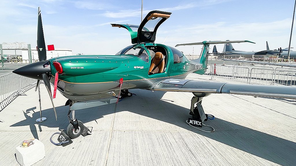 A sleek green aircraft with open doors, showcasing its luxurious interior and modern design at an airshow.