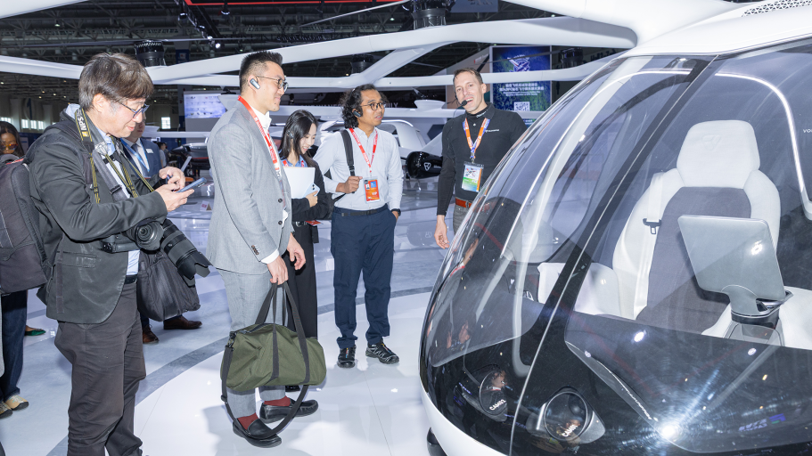 A group of four people engage in discussion near an eVTOL at an exhibition, showcasing advanced technology.