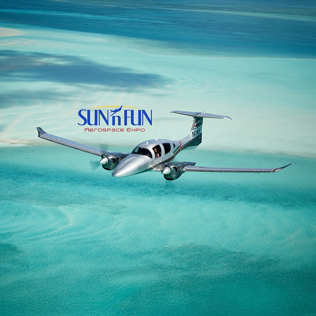 A sleek DA62 silver aircraft glides gracefully over turquoise waters, showcasing the beauty of flight and the surrounding landscape.