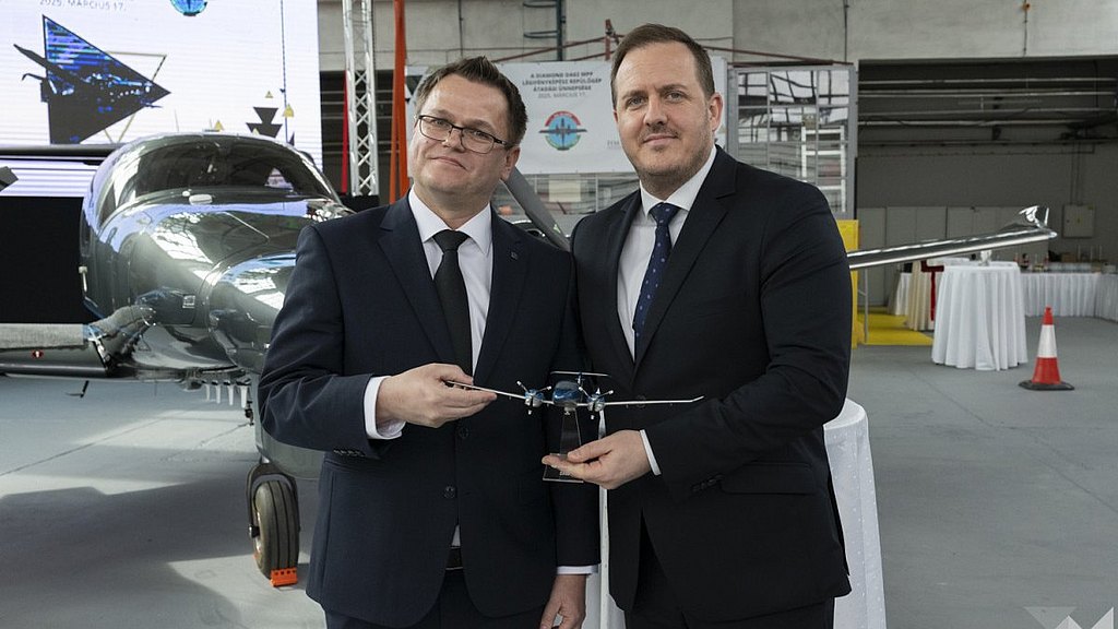 Two men holding a DA62 desk model.