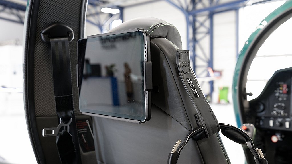 The image features a tablet securely attached to an aircraft seat, highlighting advanced aviation technology and design.