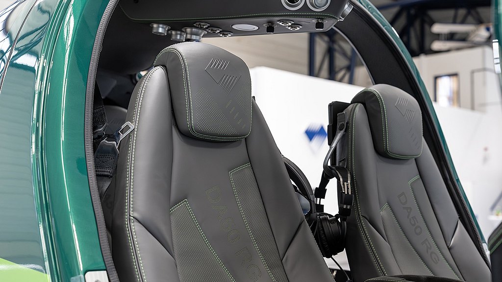 Two sleek, modern seats with green stitching are positioned inside a high-tech cockpit, showcasing a luxurious design.