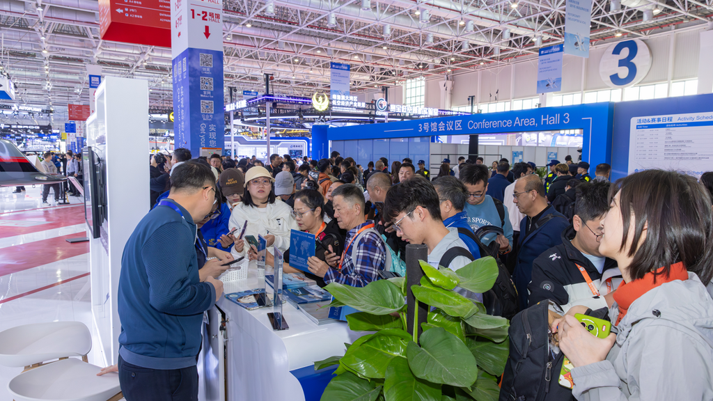 Visitors at a trade show are actively discussing and exploring products at a booth, surrounded by vibrant displays.