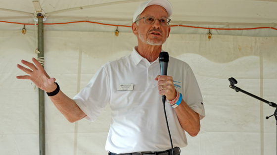Men speaking to the audience with a microphone. 