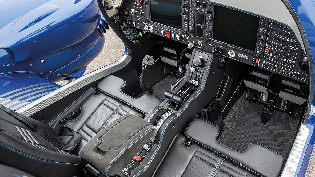 The cockpit features a sleek design with advanced controls, including a removable control stick and multiple digital displays.