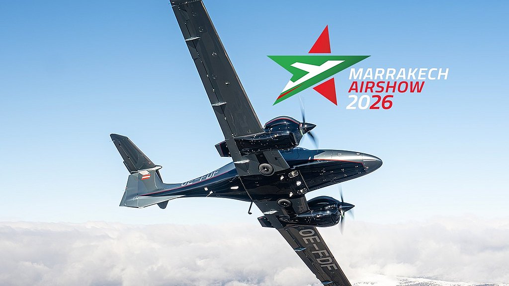 A DA62 aircraft soars through a clear blue sky, showcasing its impressive design against a backdrop of fluffy clouds.