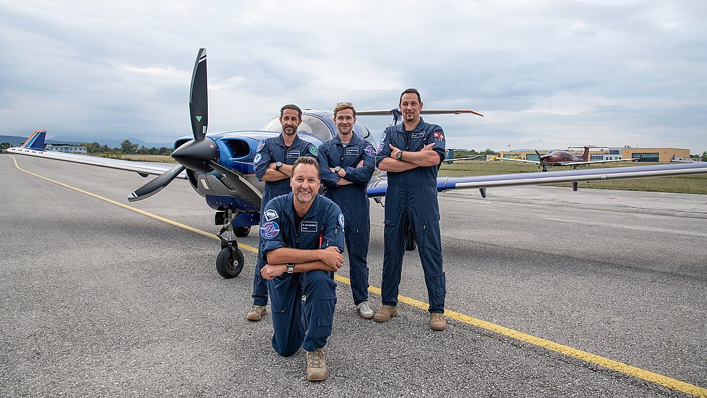 Four pilots in flight suits posing in front of a DA50 RG.