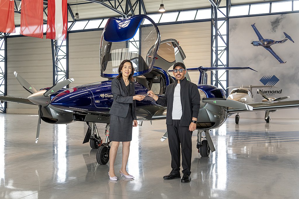 A woman and man standing in front of a blue DA42 in a hangar.