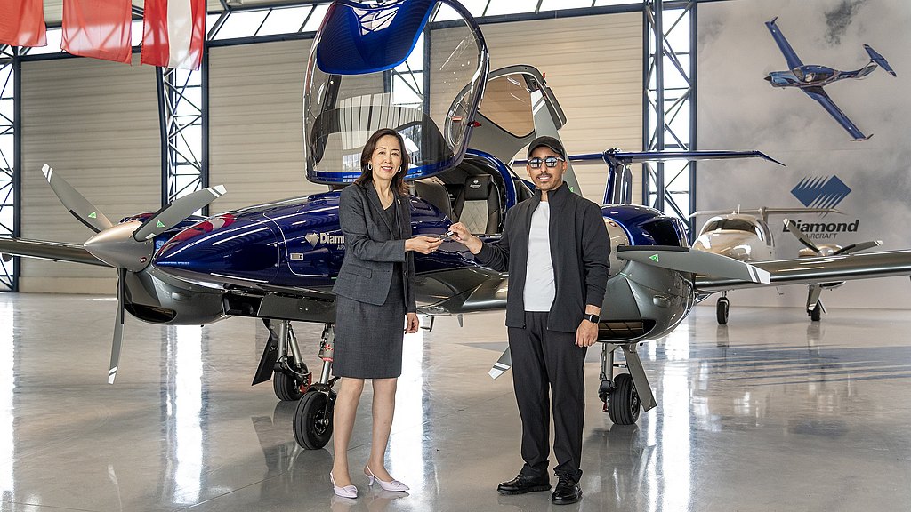 A woman and man standing in front of a blue DA42 in a hangar.