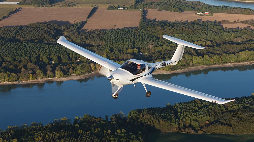 DA20-CI flying over river and fields.