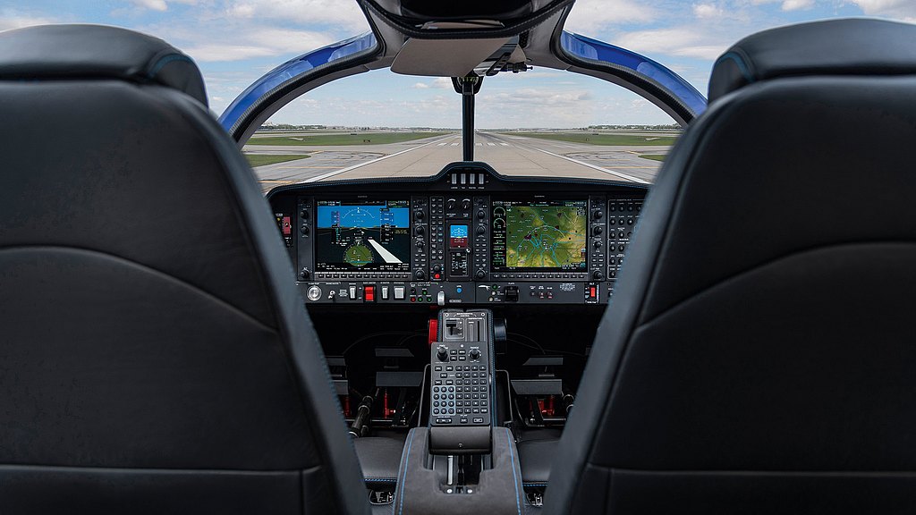 Two sleek black pilot seats frame a high-tech cockpit filled with screens displaying navigation data and flight information.