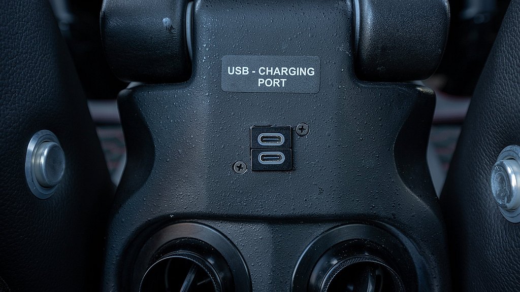 A close-up view of a USB charging port with two Type-C connectors, surrounded by a textured black surface.