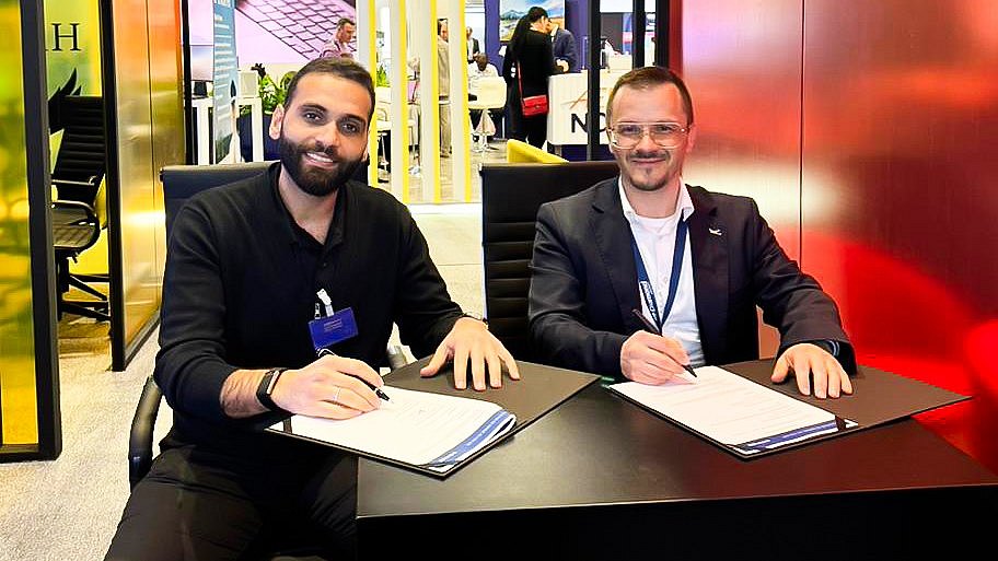 Two men sit at a table, signing documents for the Intercontinental Aviation Academy, smiling and engaged in conversation.