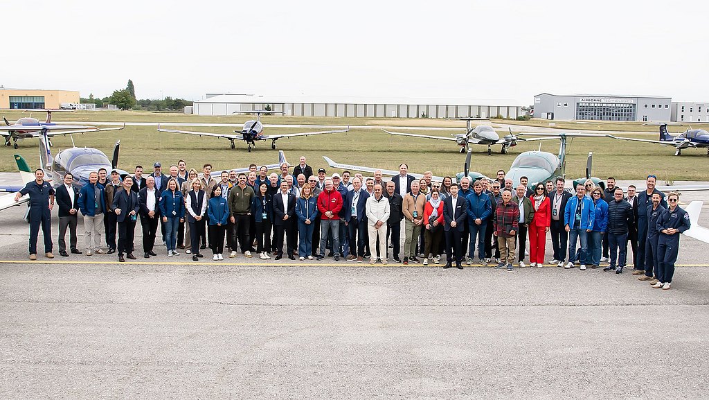 Large group of people standing on the apron with Diamond aircraft behind them. 