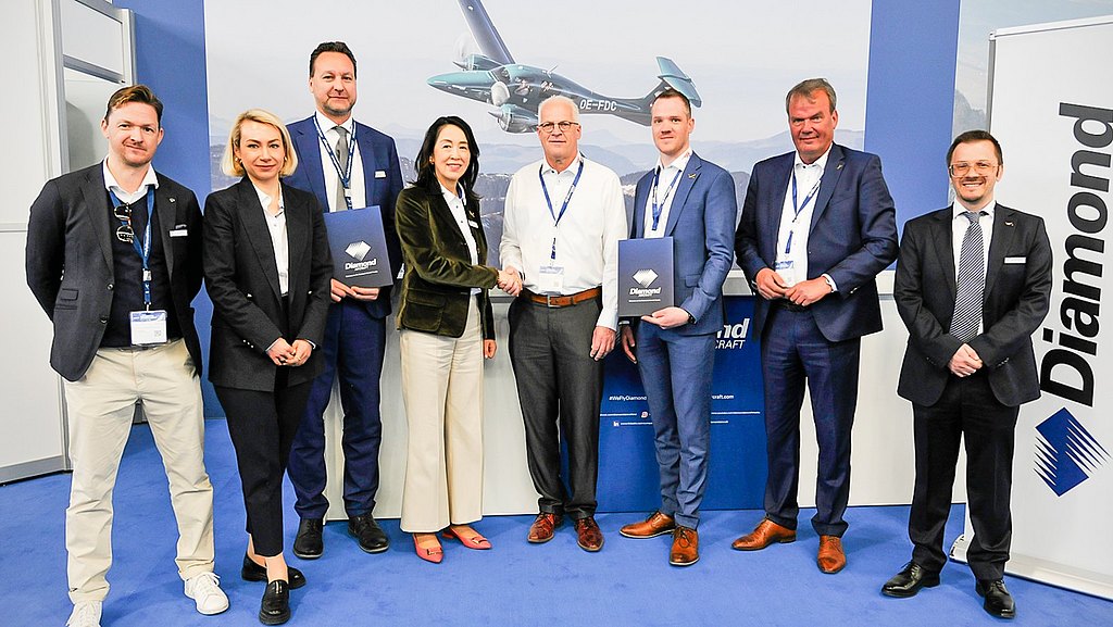 Group of people standing at the Diamond Aircraft booth during an event. 