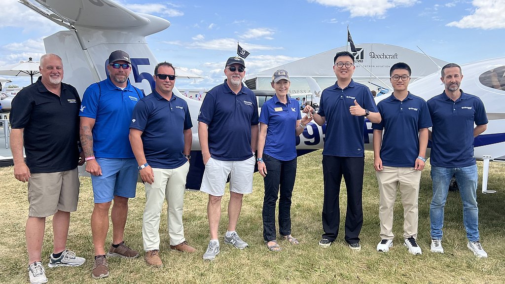 In a sunny outdoor setting, a diverse group of aviation enthusiasts smiles together, celebrating their shared passion for flying.
