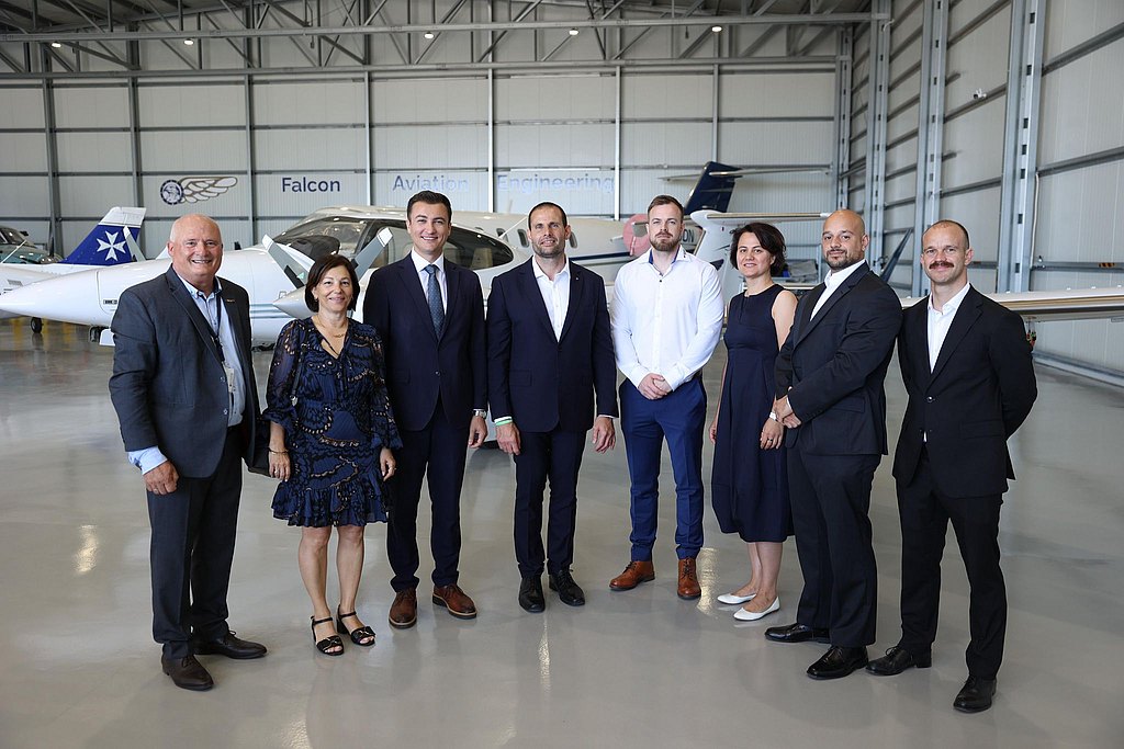 Group of people standing in an aircraft hangar in front of a DA42.