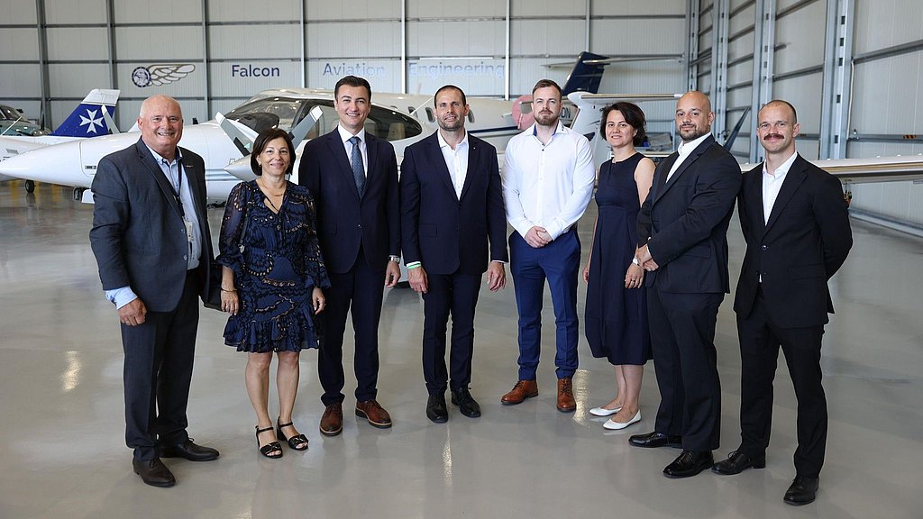 Group of people standing in an aircraft hangar in front of a DA42.
