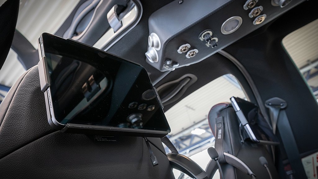 The image features a tablet attached to a seat, highlighting a sophisticated interior.