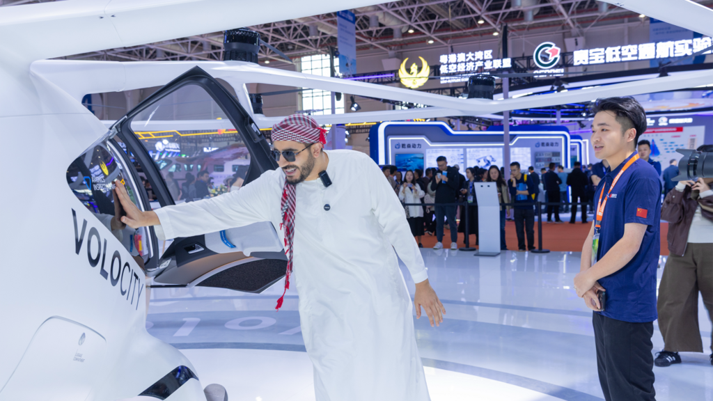 A man in traditional attire interacts with a Volocity eVTOL at a technology exhibition, showcasing innovation and excitement.