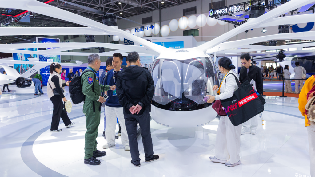 A group of people gathers around an eVTOL at an exhibition, discussing its innovative design and features.